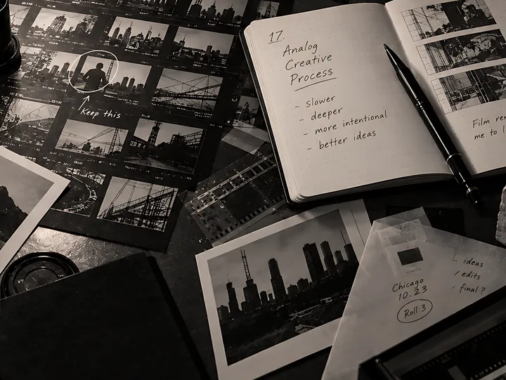 Contact sheets, film strips, a loupe and an open notebook of handwritten notes spread across a desk.